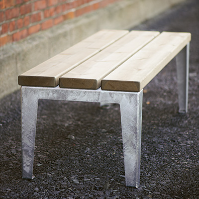 A close up of a bench made with wood and steel legs.